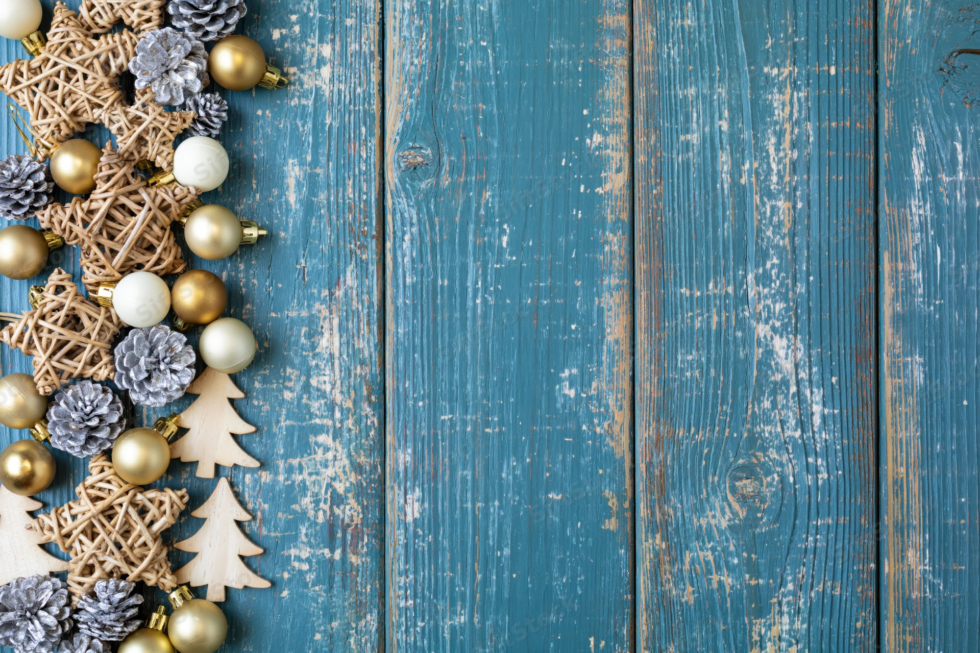 Christmas decorations arranged along left edge of weathered blue wooden surface with copyspace