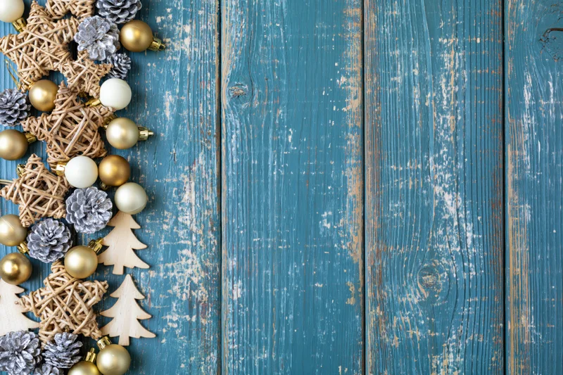 Christmas decorations arranged along left edge of weathered blue wooden surface with copyspace