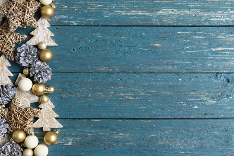 Christmas decorations arranged along left edge of weathered blue wooden surface with copyspace