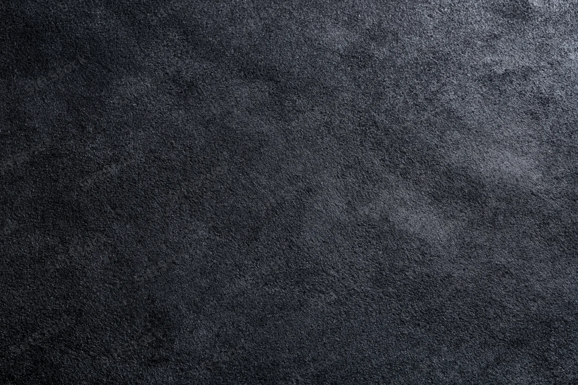 Close-up of dark black suede or matte leather surface with visible grain and texture