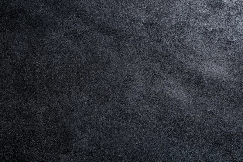 Close-up of dark black suede or matte leather surface with visible grain and texture