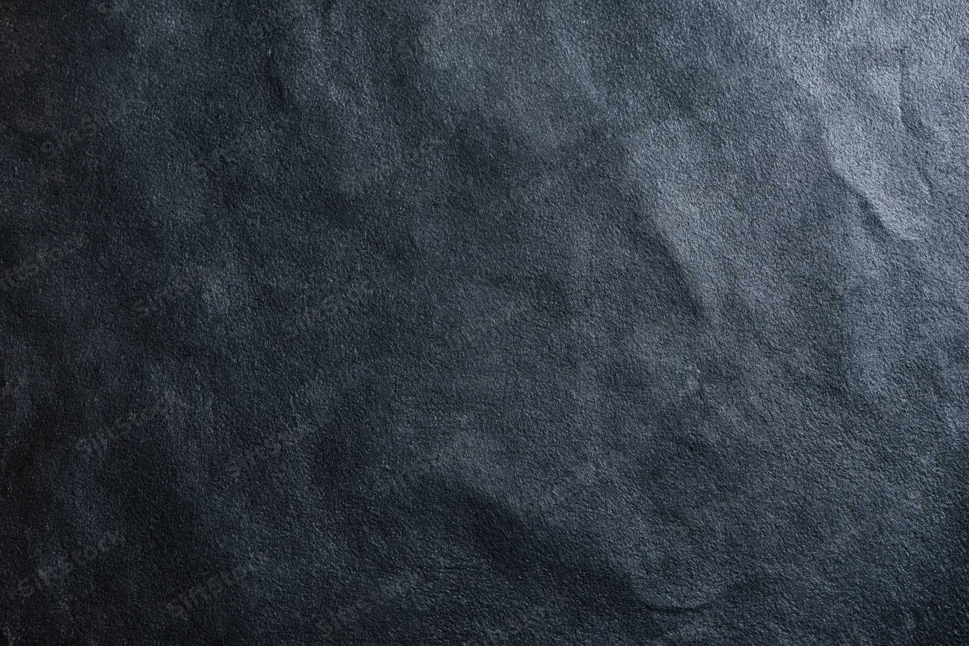 Close-up of dark black suede or matte leather surface with visible texture and grain