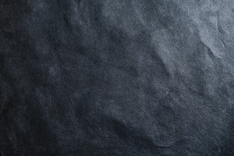 Close-up of dark black suede or matte leather surface with visible texture and grain