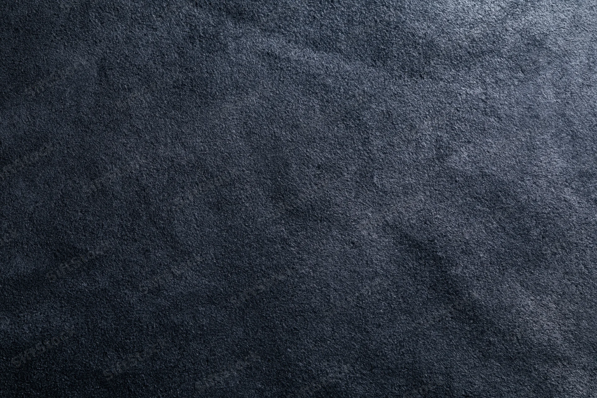 Close-up of dark matte suede or leather surface with visible texture and grain