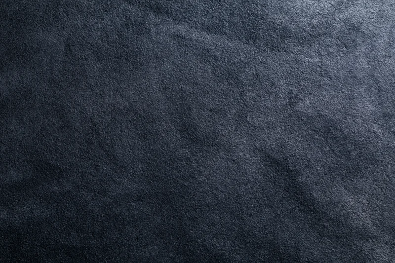 Close-up of dark matte suede or leather surface with visible texture and grain