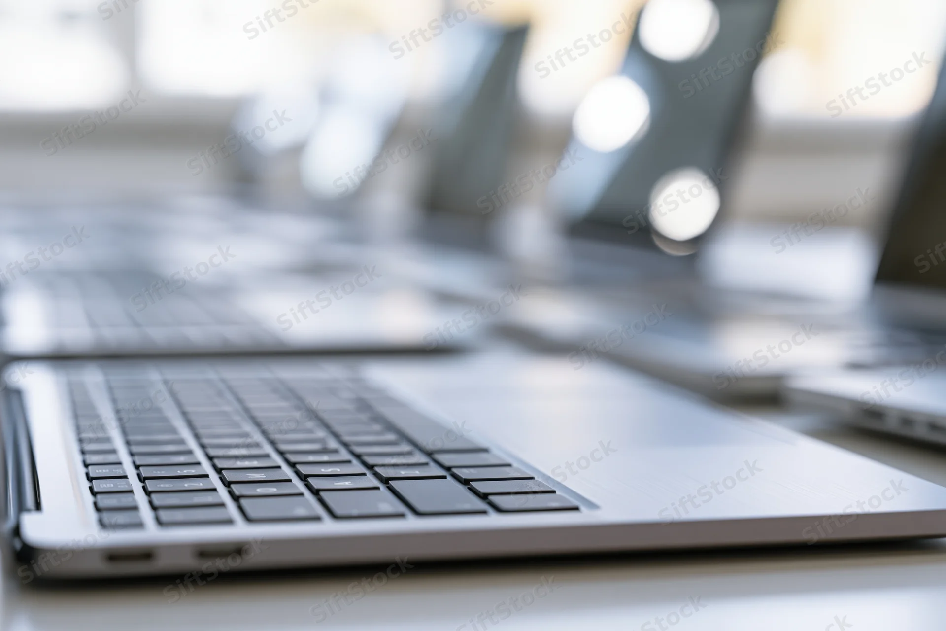 Close-up of silver laptop keyboard on a desk in a bright office workspace