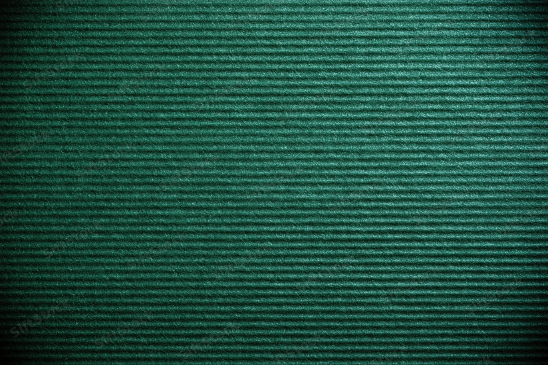 Close-up of green painted corrugated cardboard surface showing ridged texture