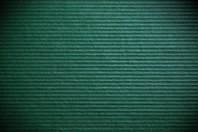 Close-up of green painted corrugated cardboard surface showing horizontal ridges and texture