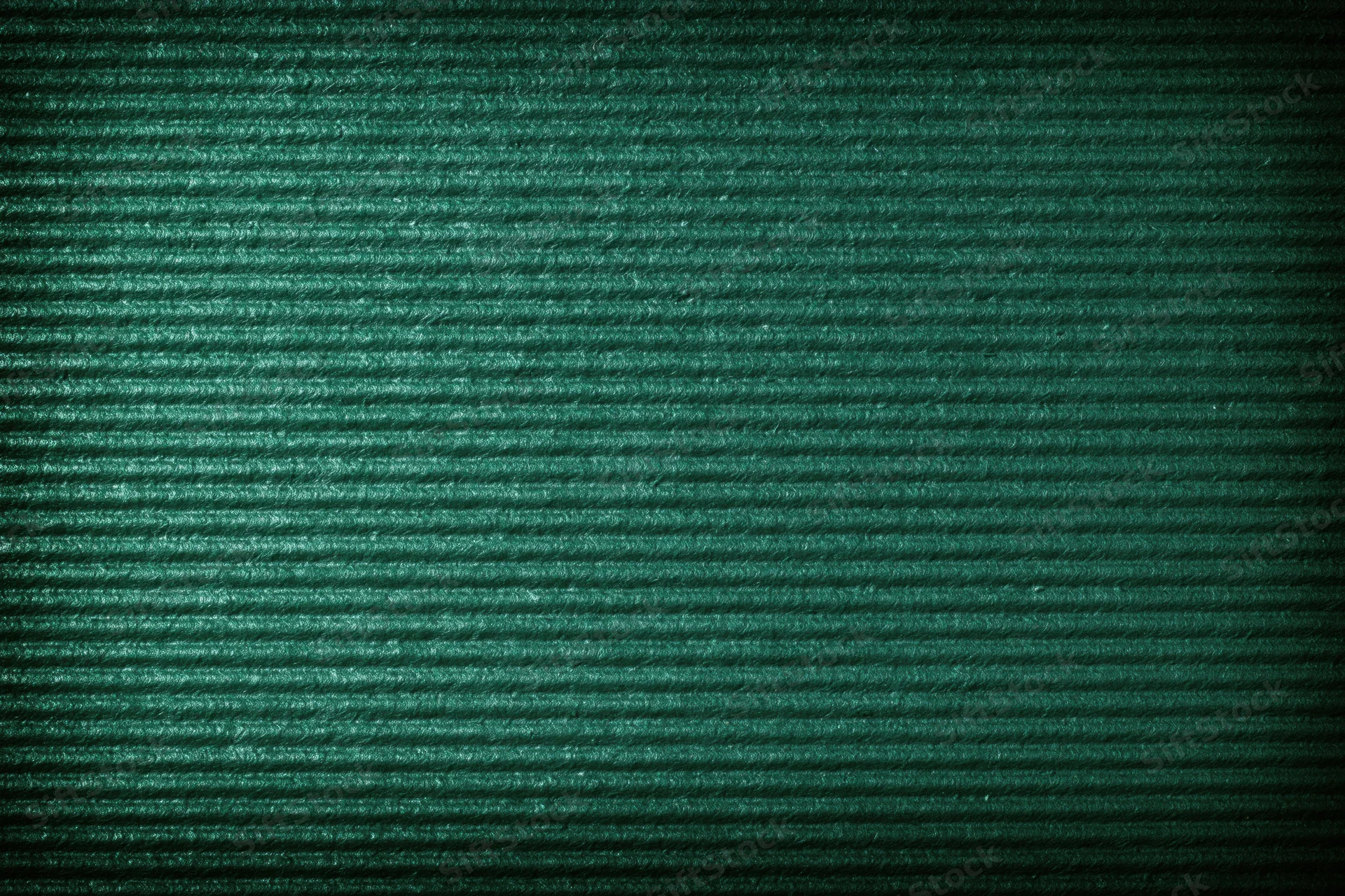Close-up of green painted corrugated cardboard surface showing ridged texture and shadow gradient