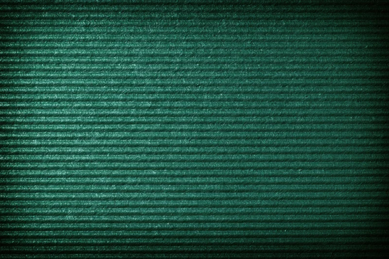 Close-up of green painted corrugated cardboard surface showing ridged texture and shadow gradient