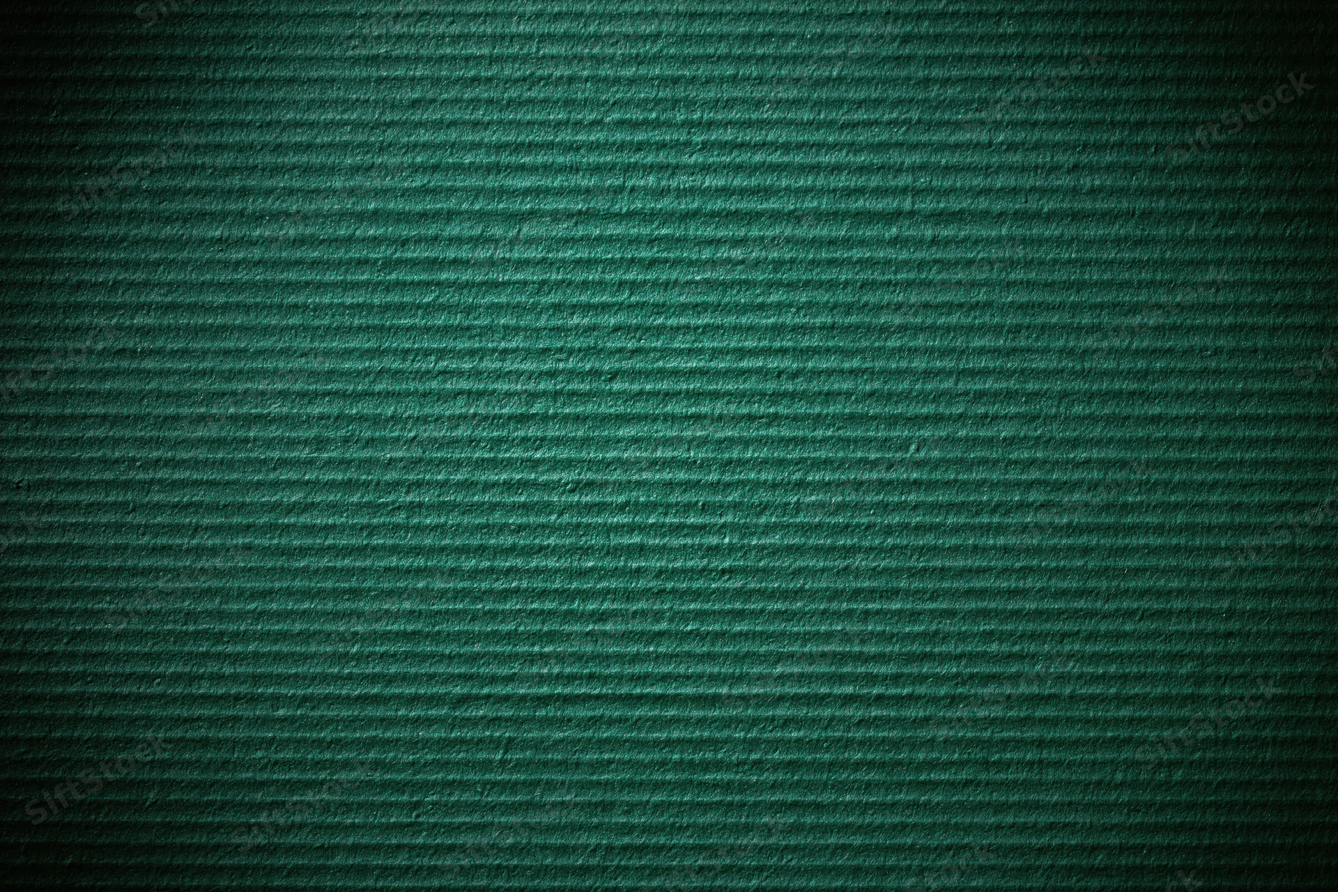 Close-up of painted green corrugated cardboard surface with ridged texture and dark vignette edges