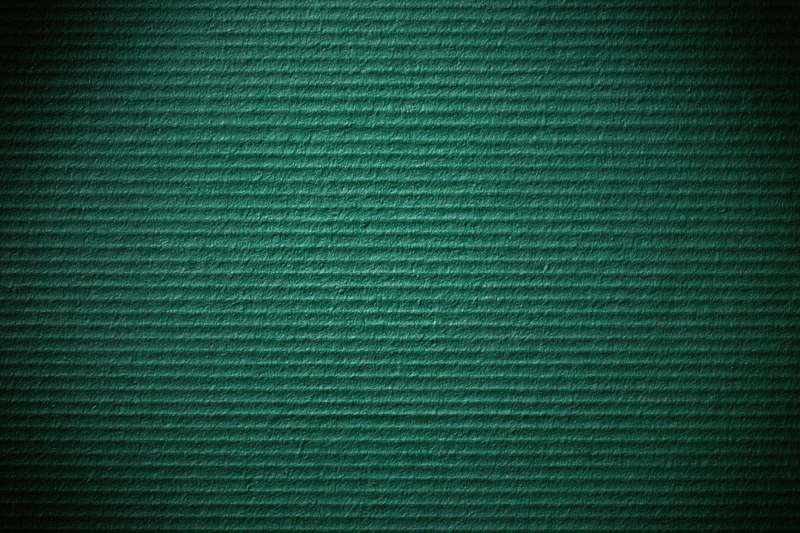 Close-up of painted green corrugated cardboard surface with ridged texture and dark vignette edges