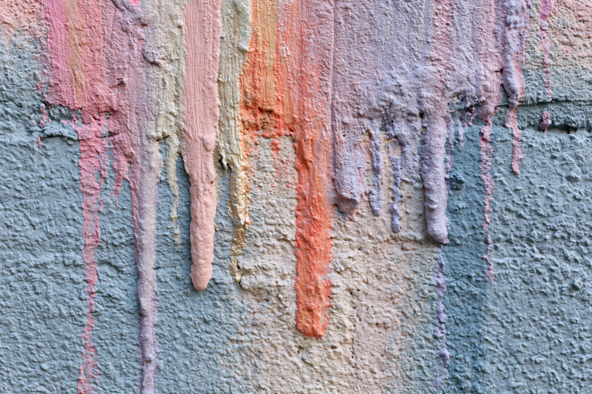 Close-up of paint drips running down a textured concrete wall