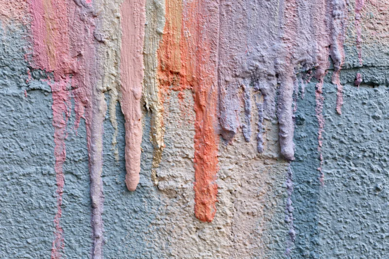 Close-up of paint drips running down a textured concrete wall