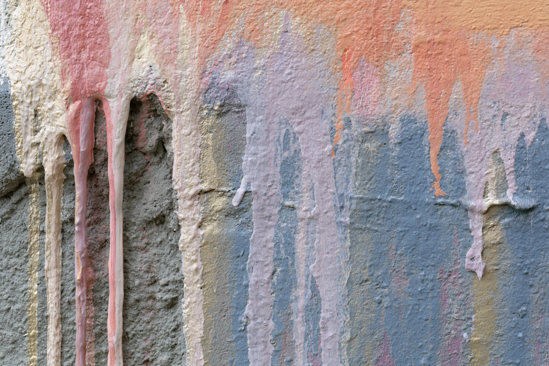 Close-up of paint drips running down a weathered concrete wall