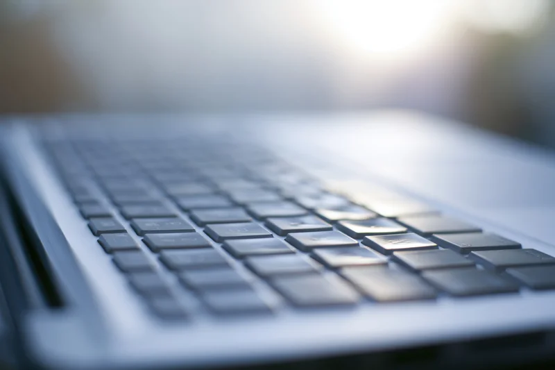 Close-up of laptop keyboard from low side angle with sunlight flare on keys