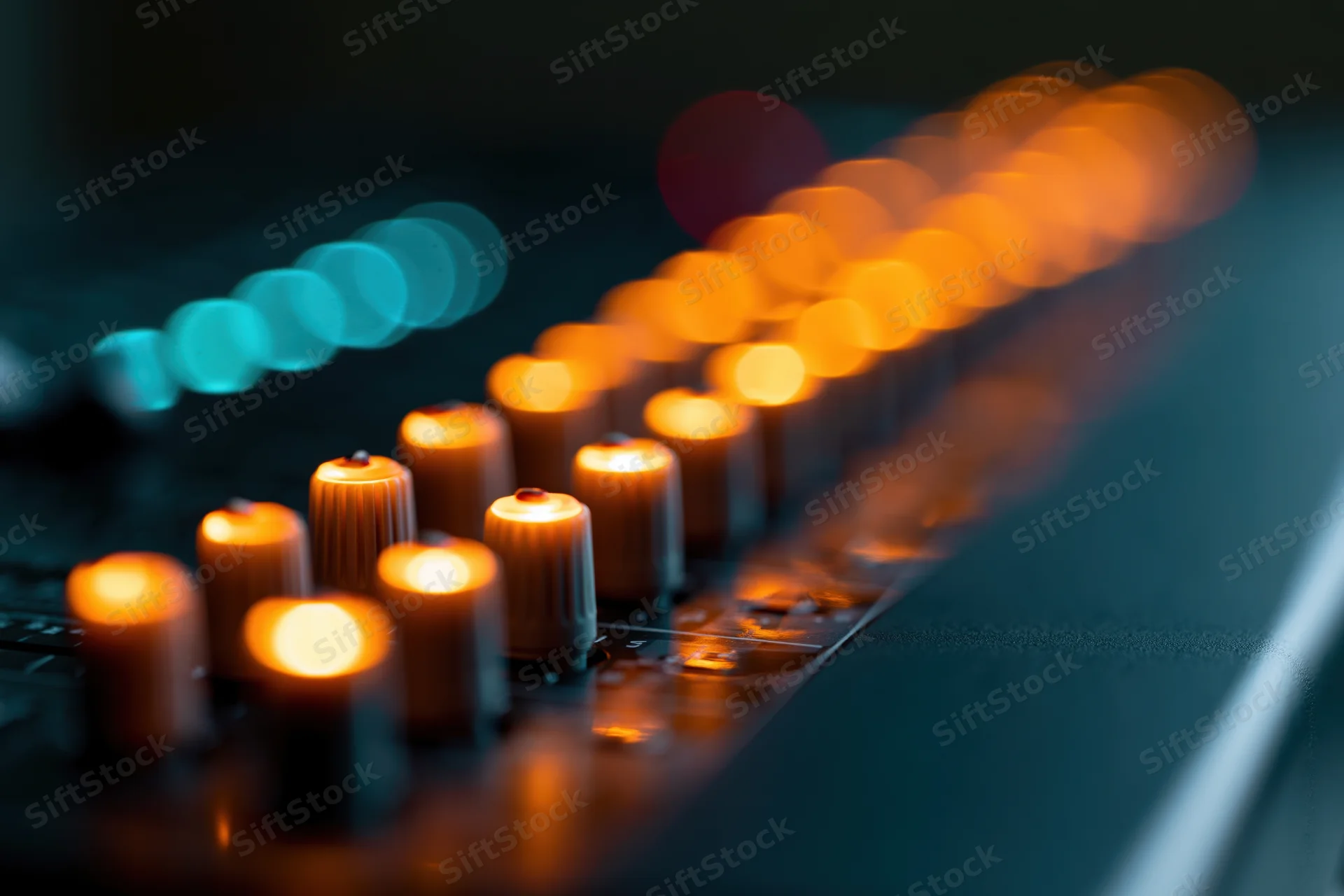 Illuminated fader knobs on a professional audio mixer console in a recording studio