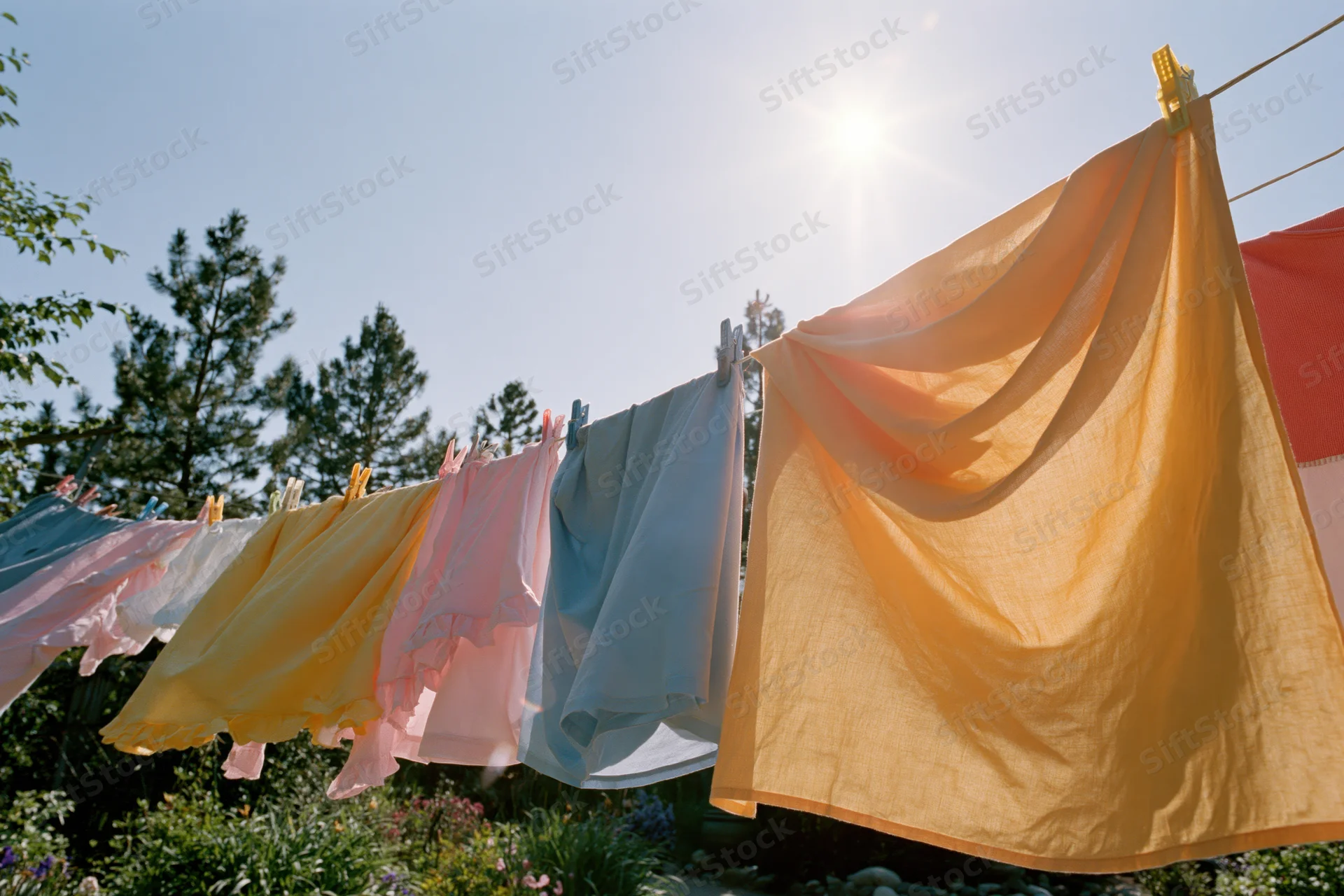 Colorful laundry hanging on an outdoor clothesline in a sunny garden
