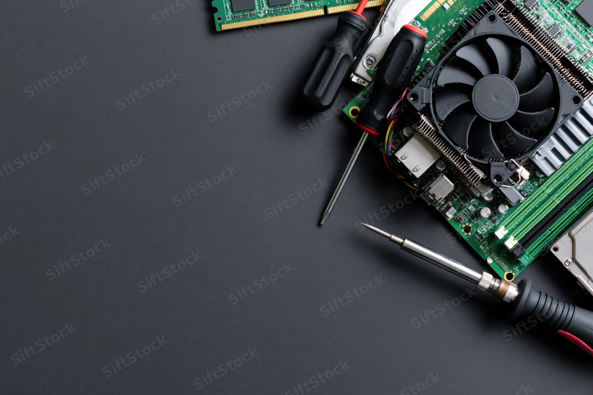 Computer hardware components and repair tools arranged on dark surface