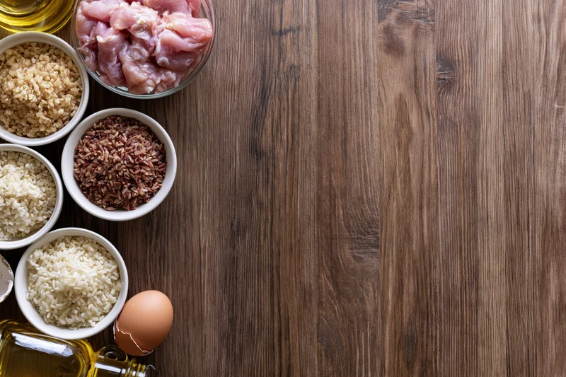 Various cooking ingredients arranged in bowls on a dark wooden table with copyspace on the right