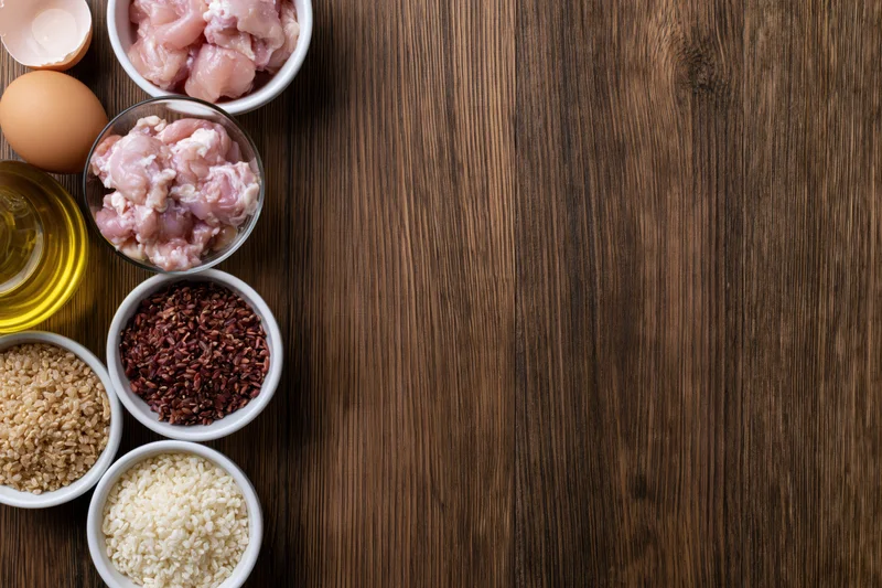 Cooking ingredients arranged in bowls on a dark wooden table with copyspace