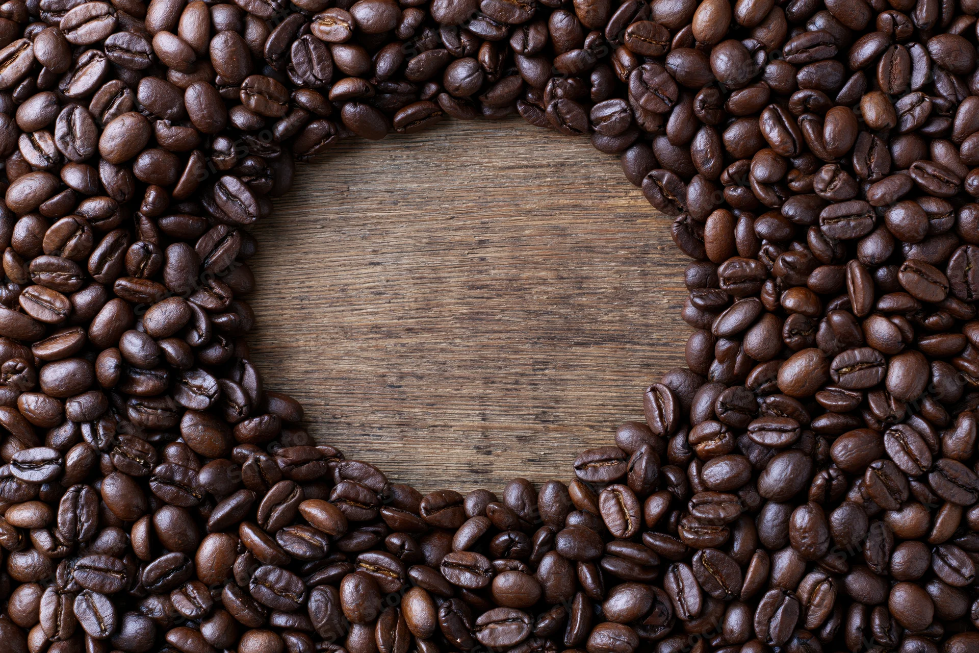 Coffee beans arranged in a border around a wooden surface with central copyspace