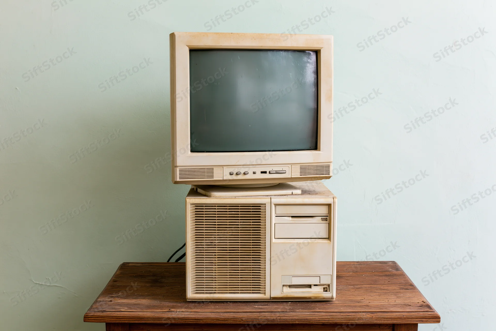 Vintage beige crt monitor stacked on old desktop computer tower on wooden desk