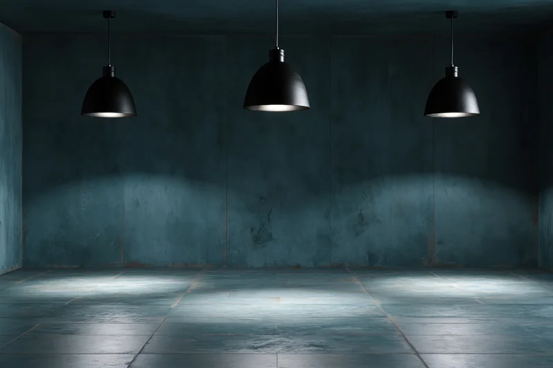Empty industrial room with three black pendant lamps hanging from ceiling, casting light on concrete floor and walls