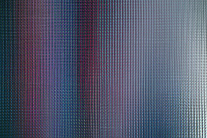 Extreme close-up of an lcd screen surface showing pixel grid and color variation
