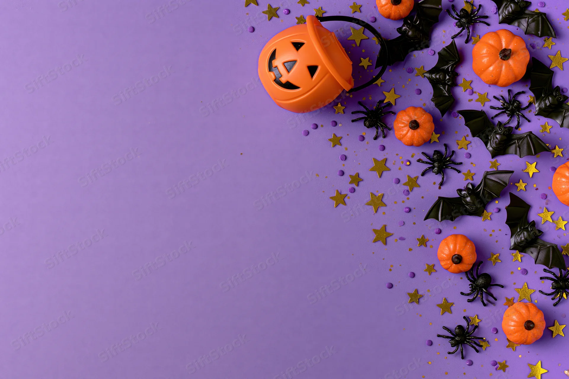 Halloween decorations arranged on purple background with copyspace on left