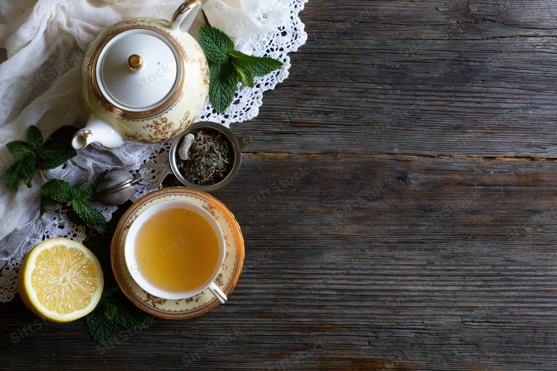 Porcelain teapot and teacup with mint and lemon on wooden table in flat lay arrangement