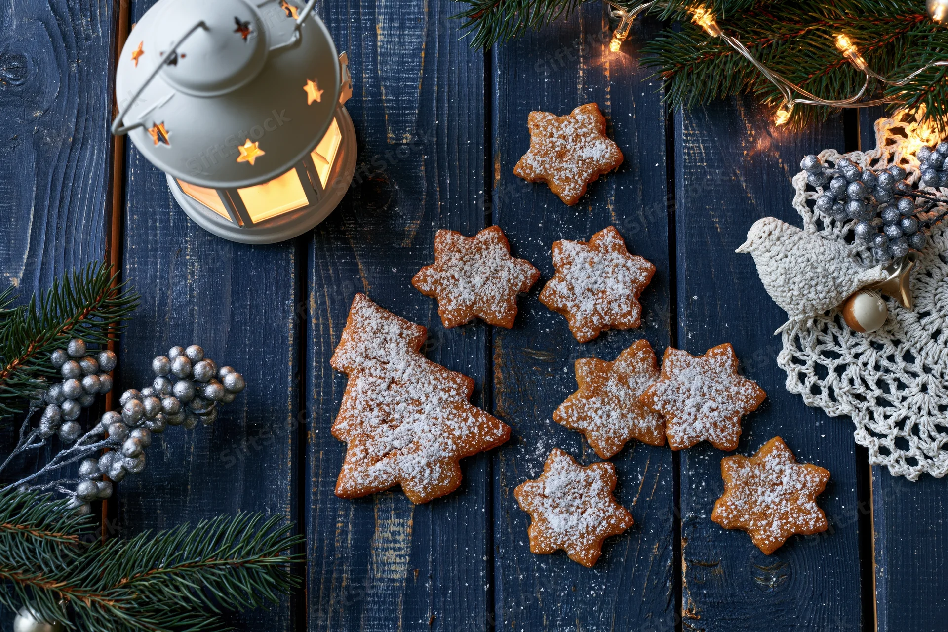 Gingerbread cookies shaped as christmas trees and stars on a dark wooden table with festive decorations