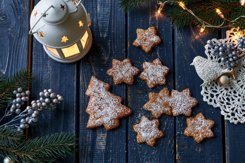 Gingerbread cookies shaped as christmas trees and stars on a dark wooden table with festive decorations