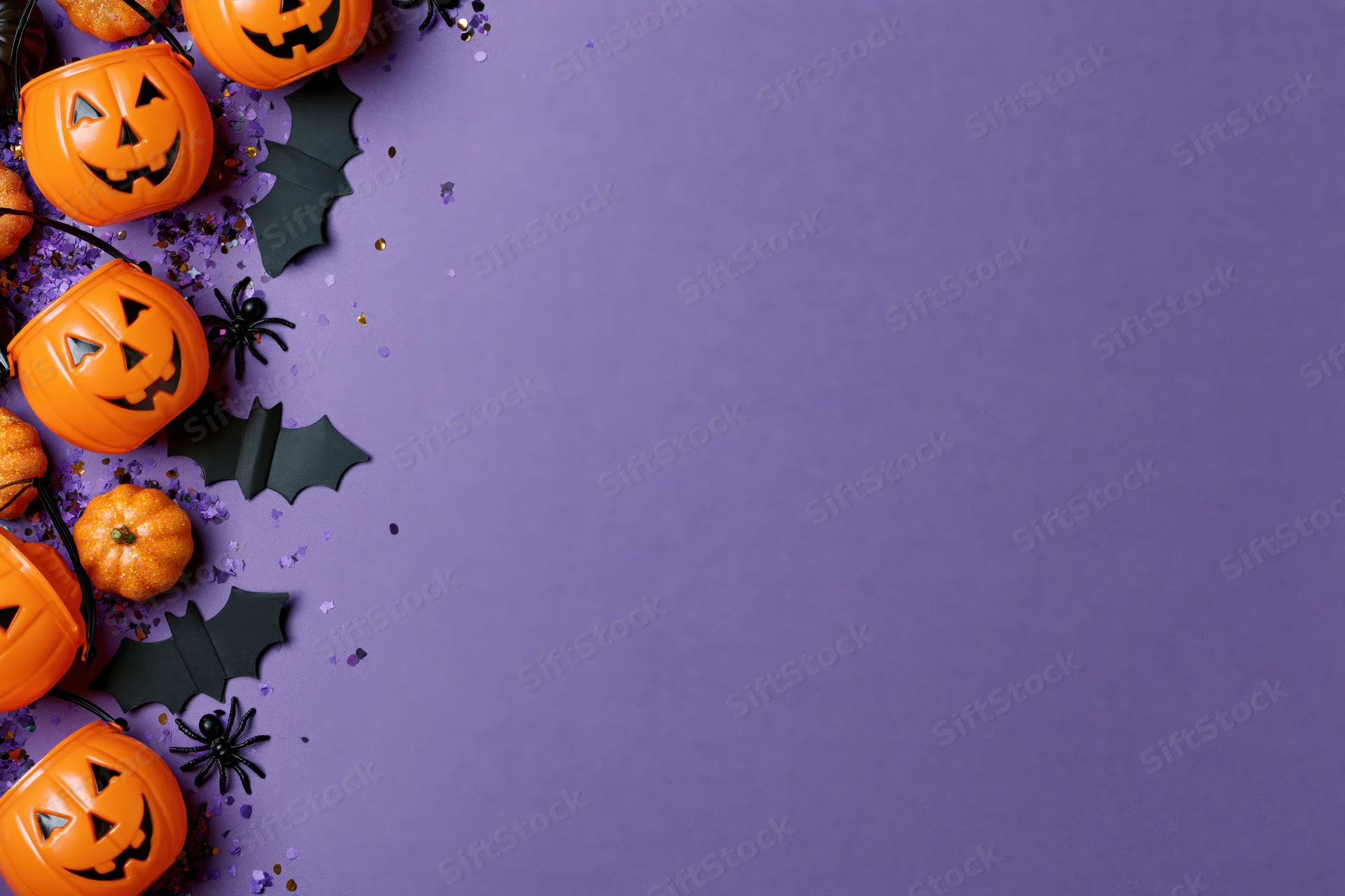 Orange plastic jack-o-lantern candy buckets and black bats arranged along left edge on purple background with copyspace