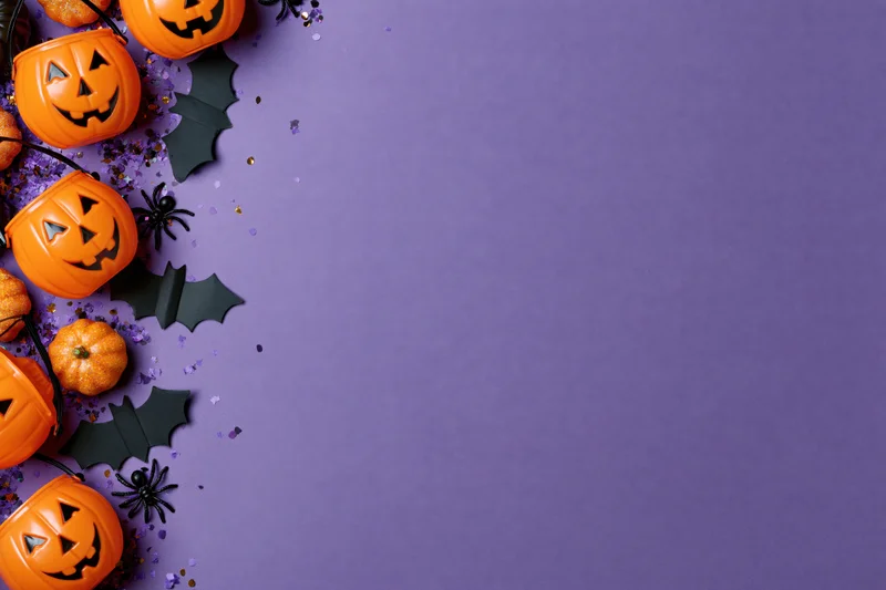 Orange plastic jack-o-lantern candy buckets and black bats arranged along left edge on purple background with copyspace
