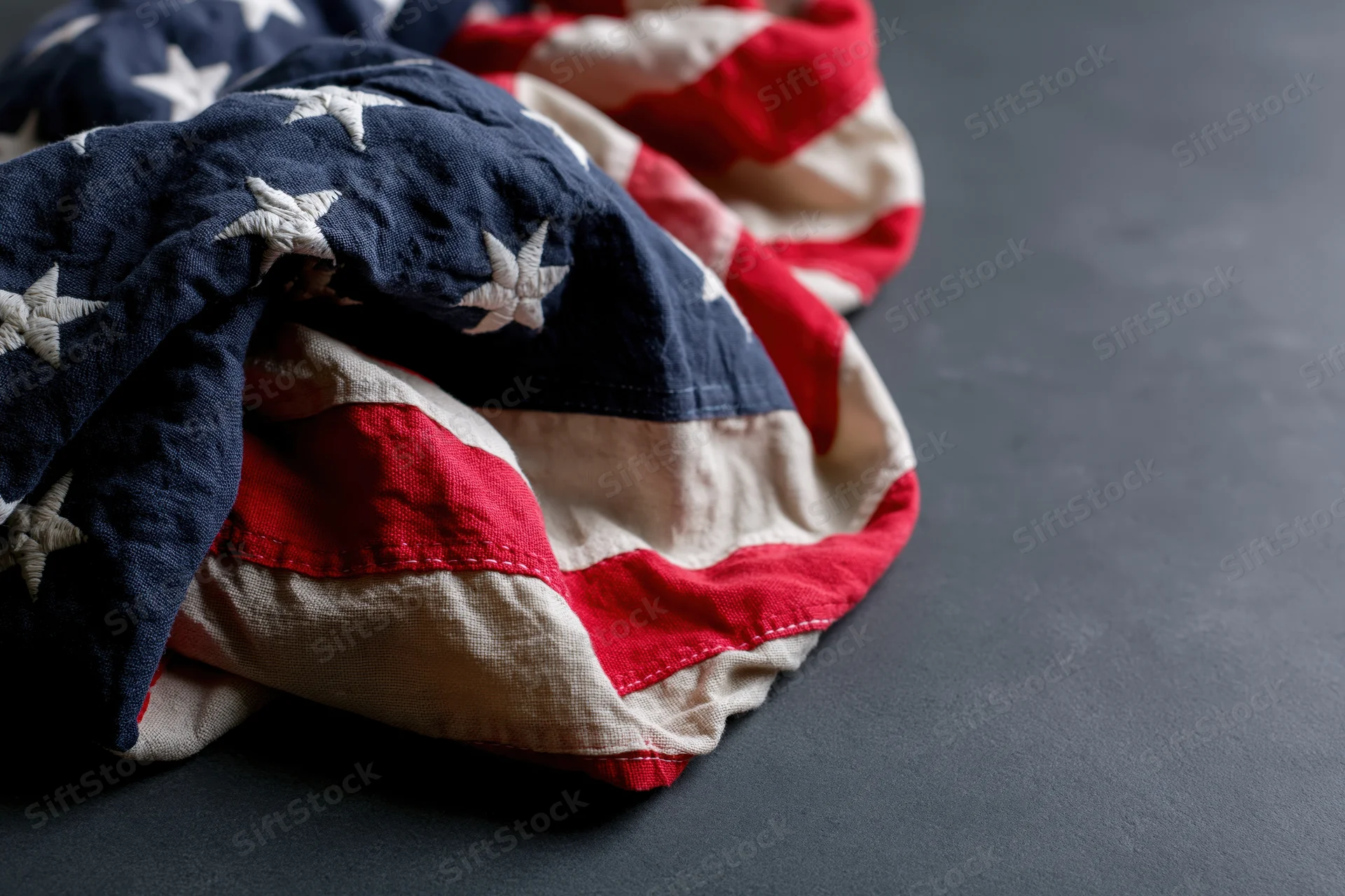 Crumpled american flag with stars and stripes resting on dark surface