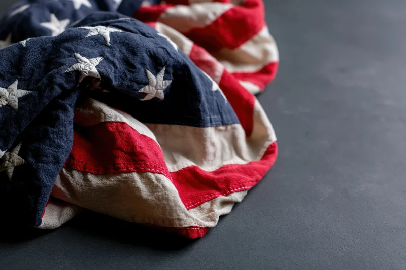 Crumpled american flag with stars and stripes resting on dark surface