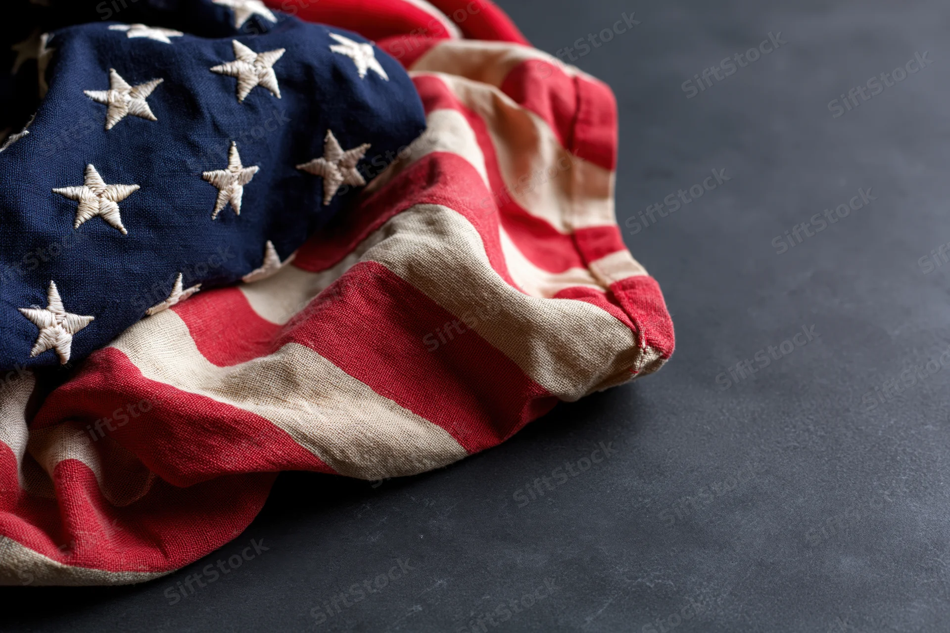 Crumpled american flag with stars and stripes resting on dark surface