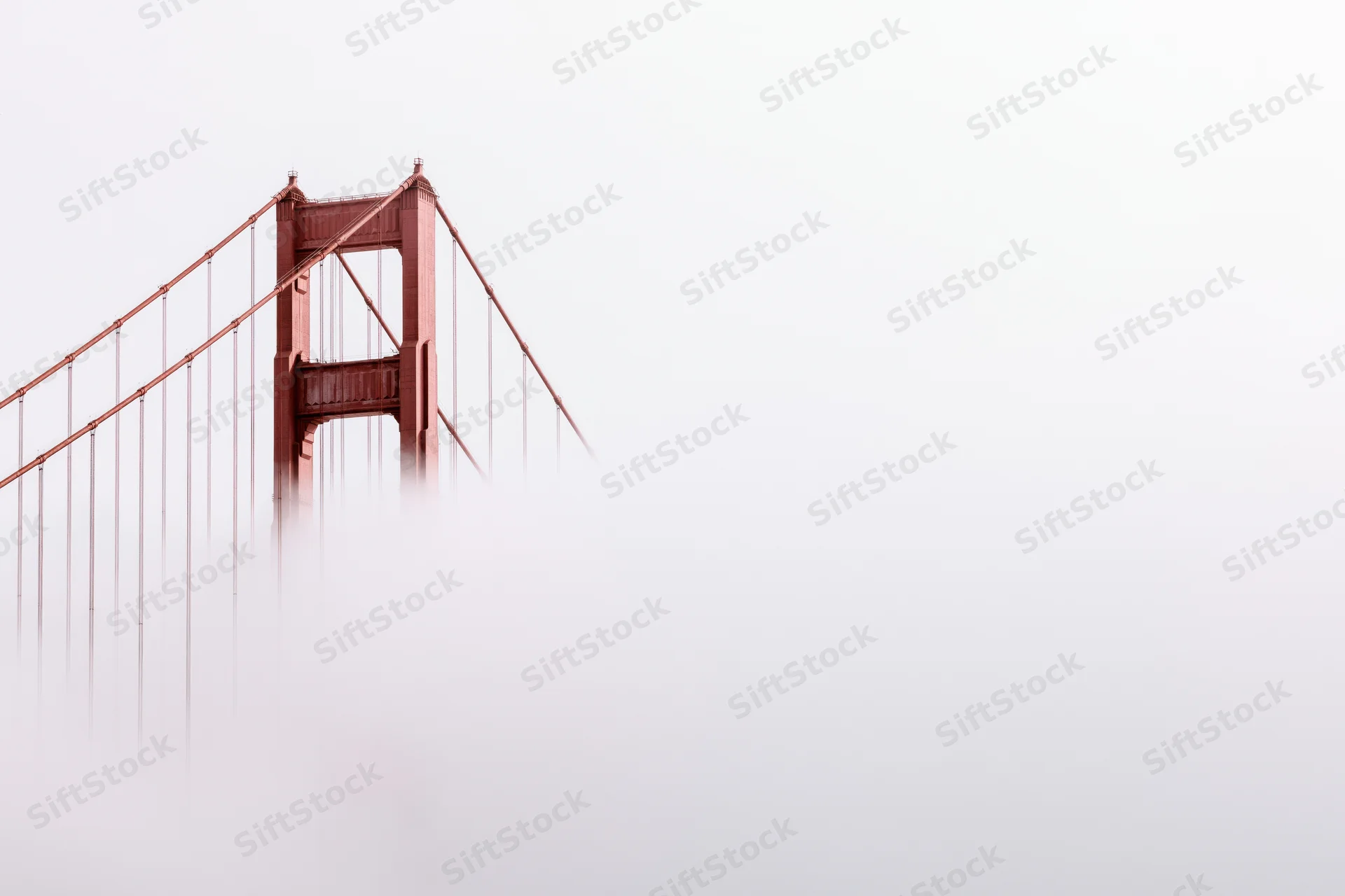 Golden gate bridge tower emerging from dense fog over san francisco bay