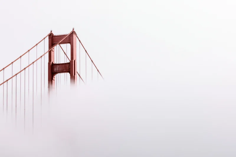 Golden gate bridge tower emerging from dense fog over san francisco bay