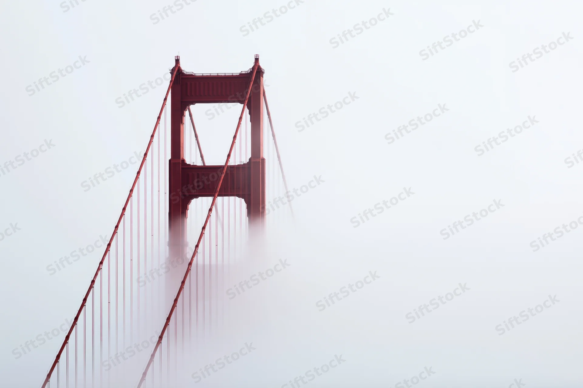 Golden gate bridge tower emerging from dense fog over san francisco bay
