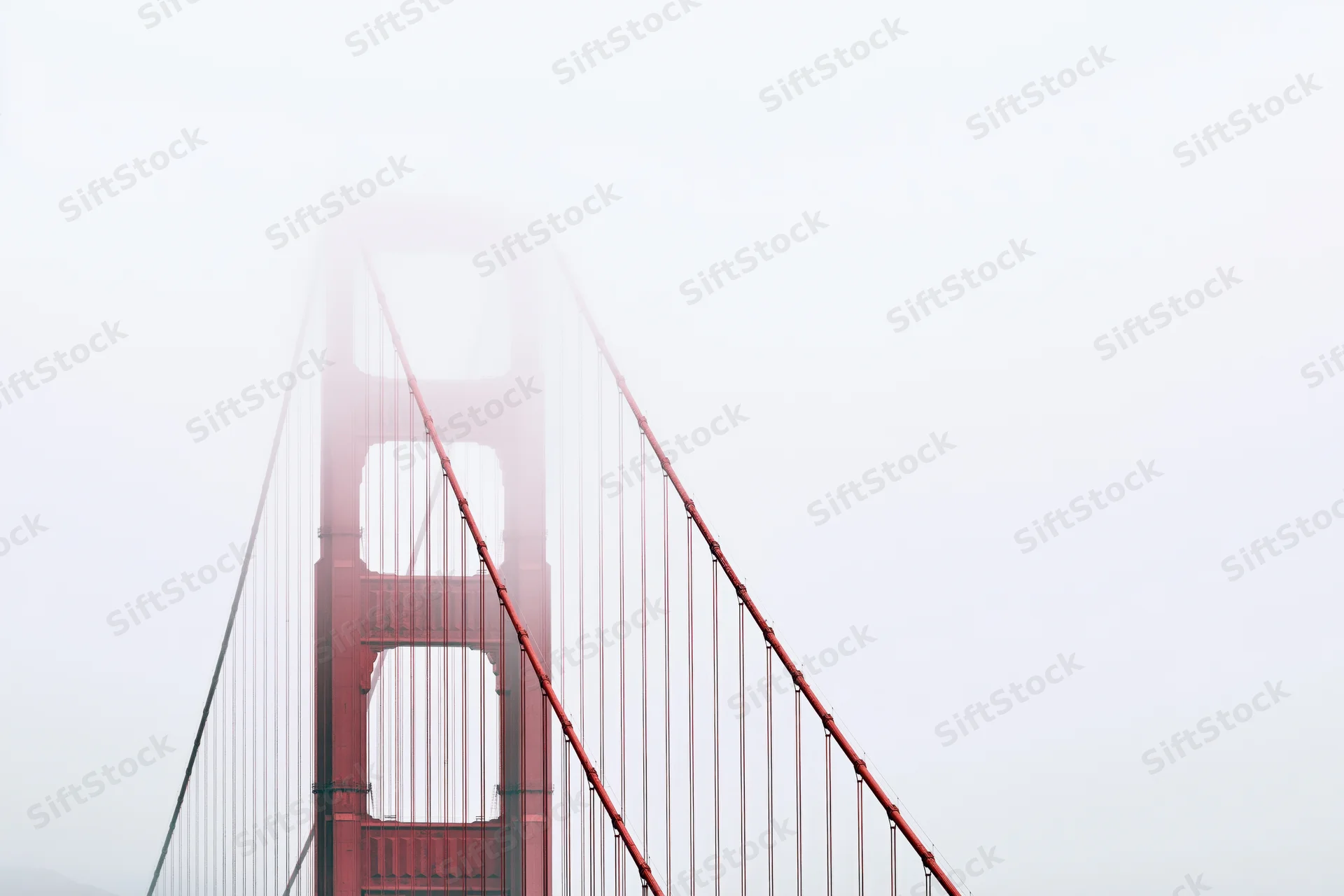 Golden gate bridge tower emerging from dense fog in san francisco