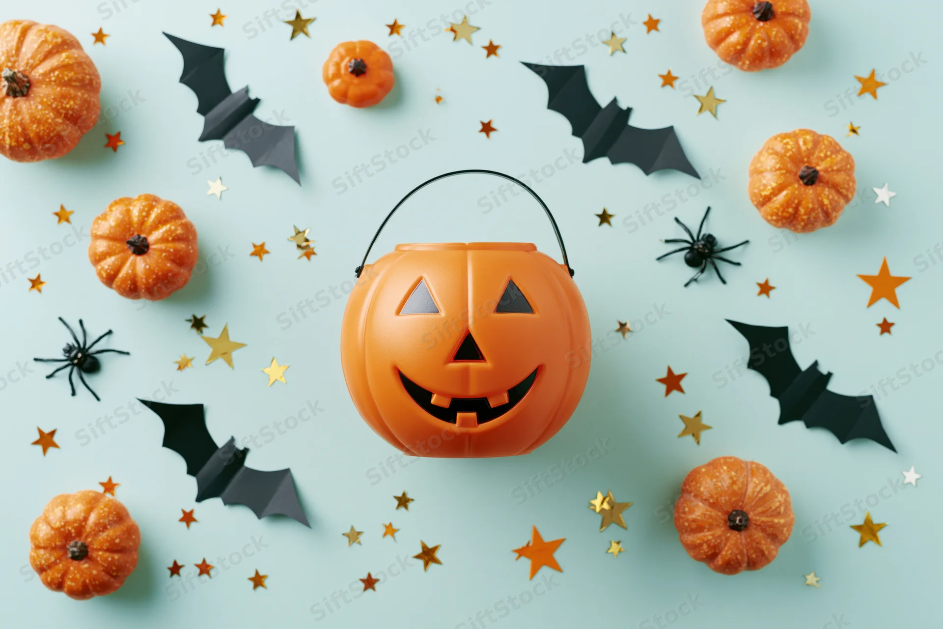 Smiling jack-o-lantern candy bucket surrounded by pumpkins, bats, spiders and stars on light blue background