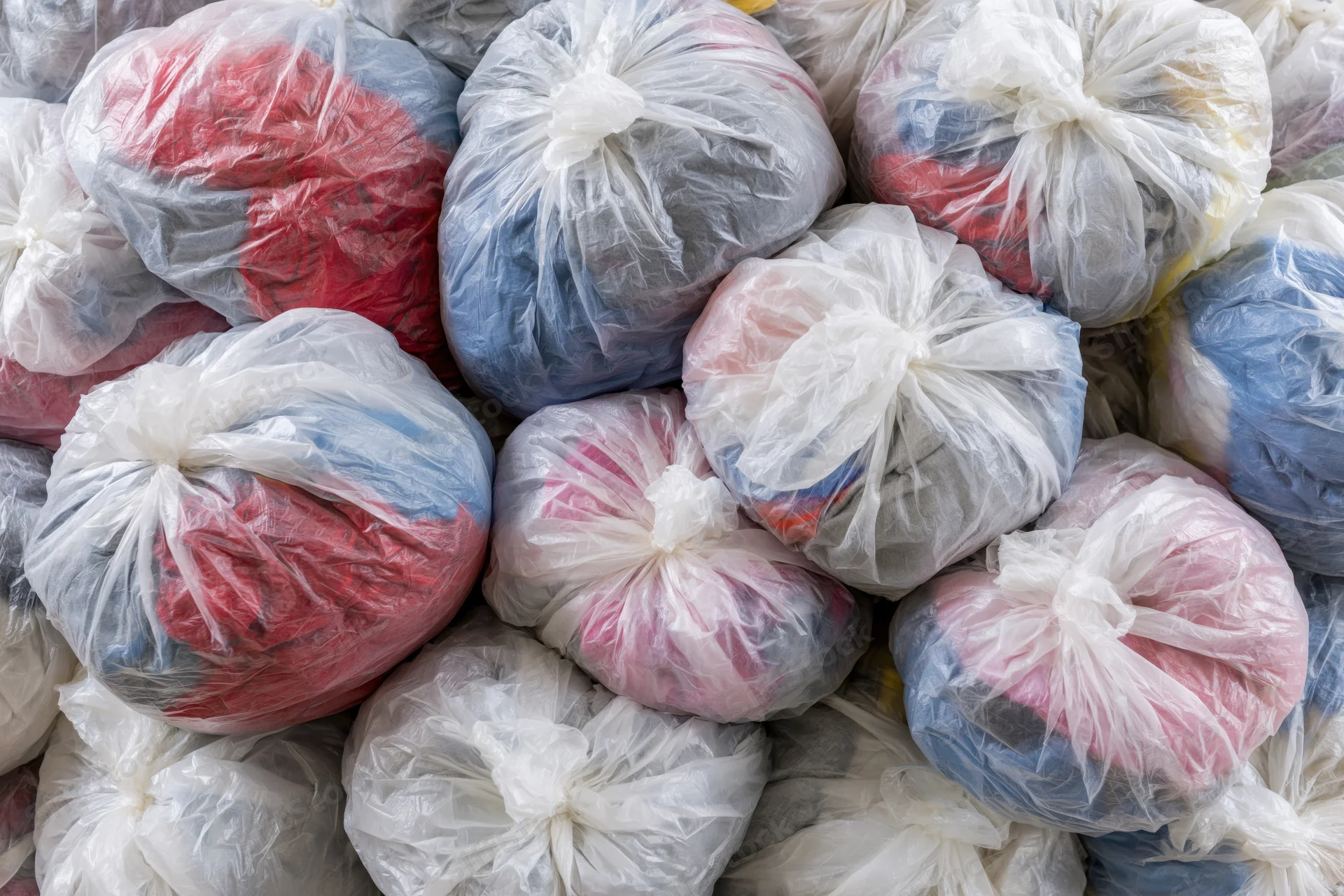 Pile of clear plastic bags stuffed with secondhand clothing for donation