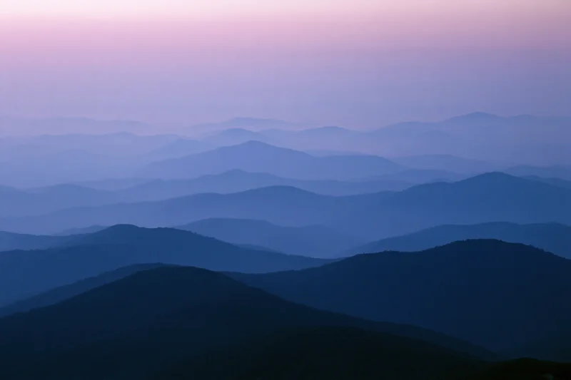Layered mountain ridges receding into hazy distance at twilight