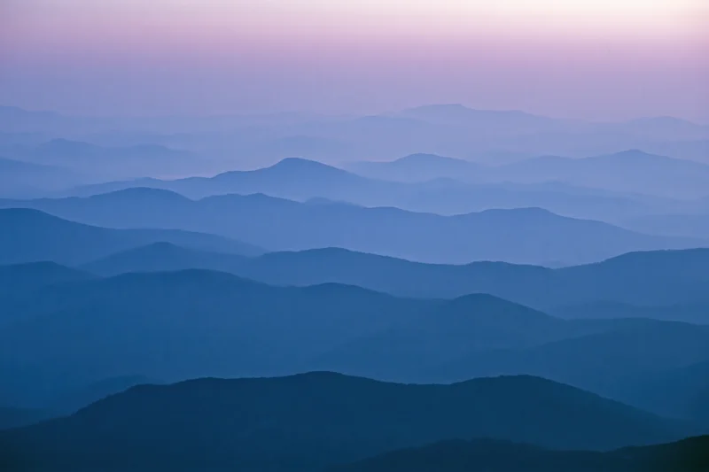 Layered mountain ridges receding into hazy distance at twilight