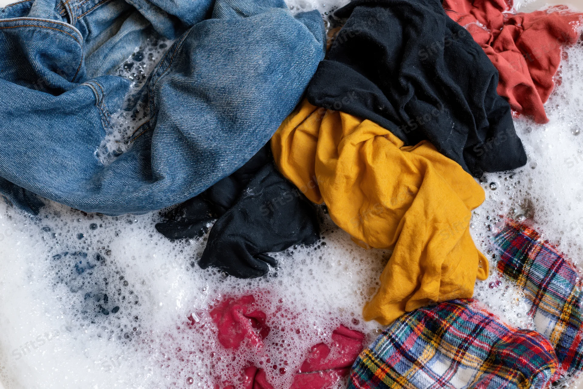 Mixed clothing soaking in soapy water in a basin