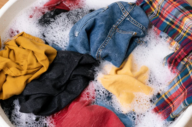 Mixed clothes soaking in soapy water in a basin