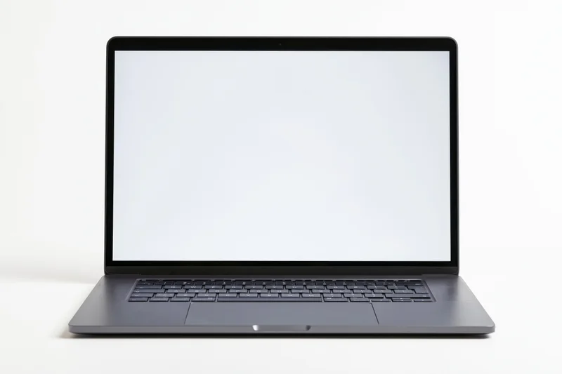 Open dark aluminum laptop with blank white screen on white surface