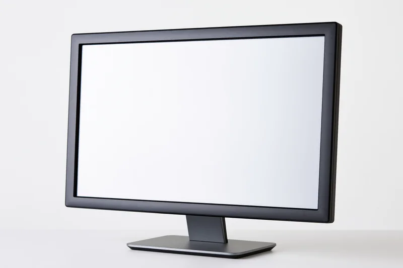 Modern flat-screen computer monitor with blank white screen on white surface